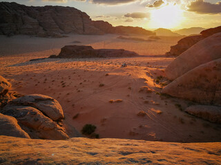 Fototapeta premium Wadi Ram desert valley surrounded by mountains, car rides in the valley, evening sun illuminates the landscape, nature of Jordan
