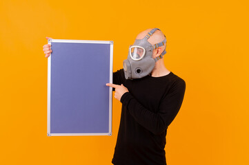 Funny strange man in respirator posing with a board  over orange background