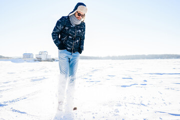 Dreaming stylish man in sunglasses posing in the snow field