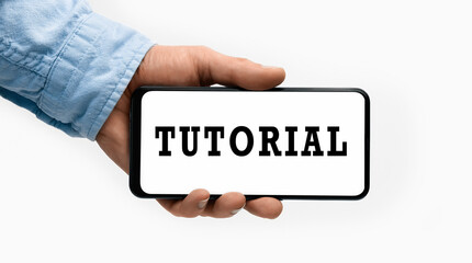 Closeup of a male hand holding Smartphone with word Tutorial on display