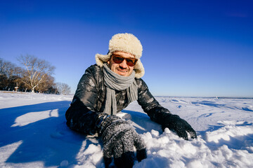 Fototapeta na wymiar Happy smiling man in sunglasses posing in the snow outdoors