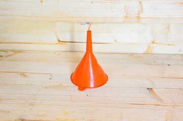 small orange plastic funnel on wooden workbench