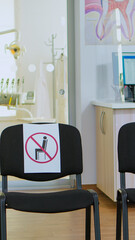 Dental clinic reception with nobody in it modern equipped with signs on chairs for social distance during global pandemic. Empty stomatology reception with new normal in covid-19 epidemic.