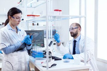 Young scientist analysing and doing experiments chemistry lab. Team of chemical chemists working together in sterile microbiology lab doing research.