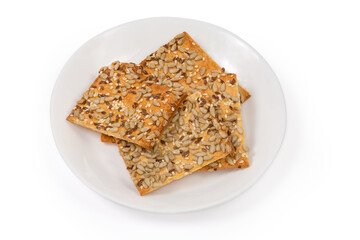 Flat flaky cookies sprinkled with different seeds on white dish