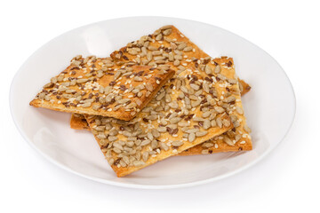 Flat flaky cookies with different seeds on dish, close-up