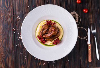 Stewed lamb tongues with red currants on a white plate. Restaurant serving. © SOLOTU