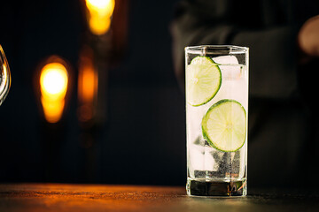 Closeup on gin tonic cocktail with rosemary and lime on the wooden table