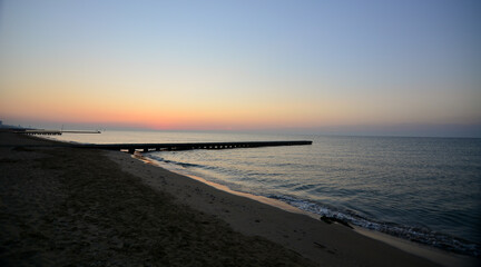 the sun rises early in the morning and illuminates the sea and the old pier