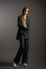 beautiful girl teenager blonde with long hair in a stylish suit in a cage posing in the studio on a gray background