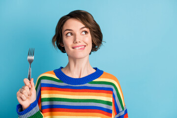 Portrait of lovely cheery minded girl holding fork looking aside copy space pondering isolated over bright blue color background