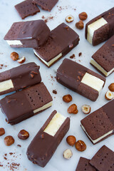 Chocolate and vanilla ice cream sandwiches with hazelnuts on light background