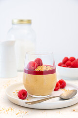 Peanuts mousse in a glass with fresh raspberries on light background