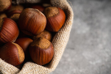 Hazelnuts in shell in pouch on the rustic background. Selective focus.
