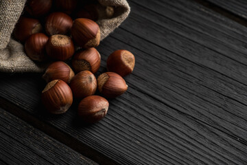 Hazelnuts in shell in pouch on the rustic background. Selective focus.
