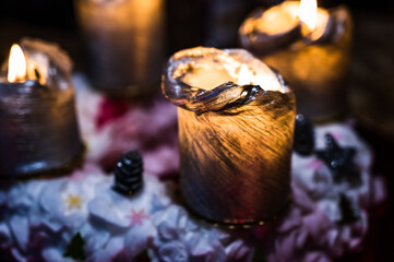 A closeup of burning golden-colored candles with Christmas decorations on a black background