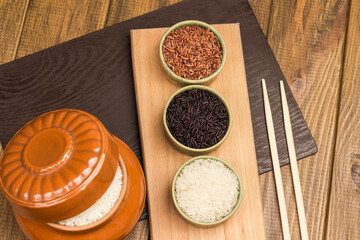 Three kinds of rice in ceramic bowls on board. White rice in ceramic bowl