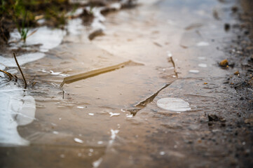 A closeup of the soil covered in frozen ice in the morning