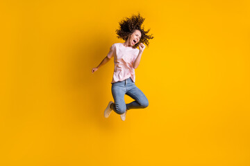 Fototapeta na wymiar Photo portrait full body view of girl screaming into imaginary microphone jumping up isolated on vivid yellow colored background