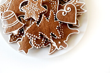 Christmas homemade gingerbread on a plate, handmade, various molds, top view on a white wooden table.