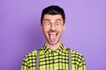 Photo portrait of funny guy showing tongue isolated on vivid violet colored background