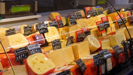 Dairy products counter in supermarket. Glass window with cheese variety on offer with reduced...
