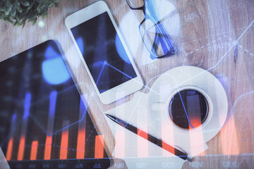 Double exposure of forex chart hologram over desktop with phone. Top view. Mobile trade platform...
