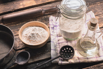 A flour in the jar and old different kitchen utensils on the table background.