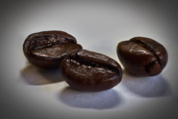 Closeup of three roasted coffee beans, on a white background