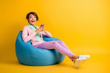 Photo of impressed brown hair bob lady dressed pink clothes sitting beanbag typing device isolated...