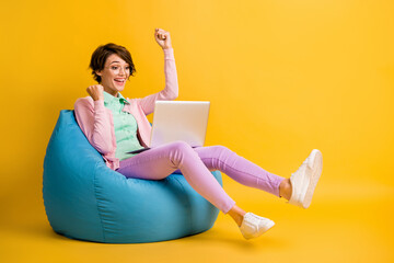 Full length body size photo happy girl sitting in beanbag browsing internet gesturing like winner...