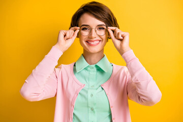 Photo of cheerful young girl hold spectacles wear eyeglasses turquoise shirt pink cardigan isolated yellow color background