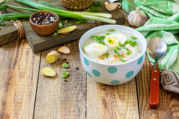 Hot soup chicken with ginger rice and garlic in a bowl on a rustic table. Copy space.