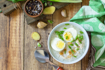 Hot soup chicken with ginger rice and garlic in a bowl on a rustic table. Top view flat lay. Copy space.