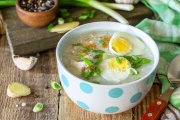 Hot soup chicken with ginger rice and garlic in a bowl on a rustic table.