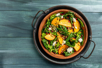 Gourmet salad with persimmon, avocado, pumpkin seeds, walnuts, pomegranate and arugula on a light background, Flat lay. Banner. Top view