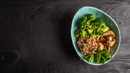 Diet salad made from fresh vegetables broccoli, mushrooms, spinach and quinoa in a bowl. Delicious breakfast or snack, Clean eating, dieting, vegan food concept. vertical image.