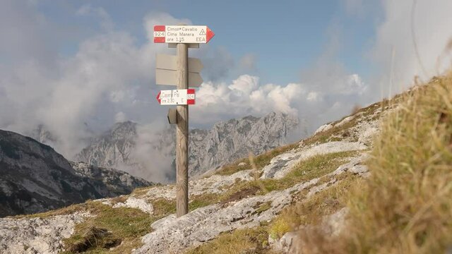 time lapse shot of high mountain panorama with low clouds and treccking trails signpost