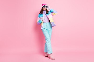 Full length photo of pretty cute woman skier dressed colorful windbreaker walking arm eyeglasses isolated pink color background