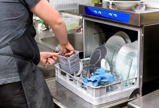 Restaurant Kitchen Worker Emptying A Dishwasher