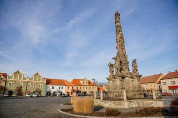Fototapeta na wymiar Marian Column at King Vladislav Square, Narrow picturesque street with colorful buildings in historic center of town Velvary in sunny day, Central Bohemia, Czech Republic