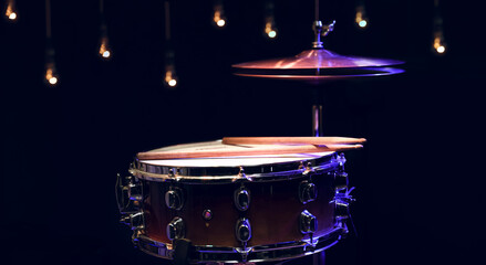 Snare drum and hi-hat in the dark on a blurred background with lights.