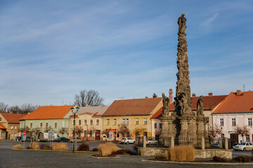 Marian Column at King Vladislav Square, Narrow picturesque street with colorful buildings in historic center of town Velvary in sunny day, Central Bohemia, Czech Republic