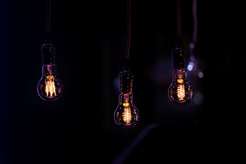 Three burning lamps on a blurred dark background.