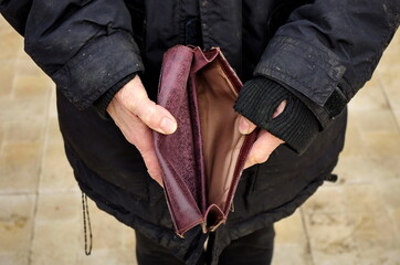 An elderly homeless poor woman holds an empty wallet, or purse. The concept of poverty in retirement. Global Extreme poverty. No money help me. Covid-19 Global Financial Crisis.