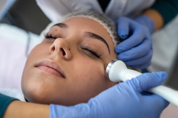 Obraz na płótnie Canvas cosmetologist using ultrasound cavitation machine doing procedure lifting therapy massage
