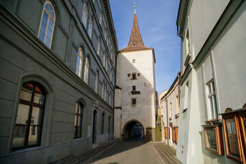 Gothic tower of the Velvary Gate, town fortifications built in the pre-Hussite period in sunny day, street of historic medieval city Slany, Central Bohemia, Czech Republic