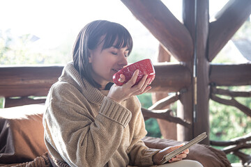 Beautiful young woman with a big red cup and a book in her hands.