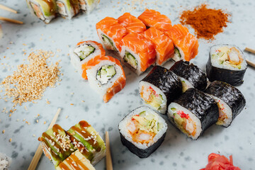 Close up view on assorted Japanese sushi food and rolls on bright table, chopsticks and ingredients