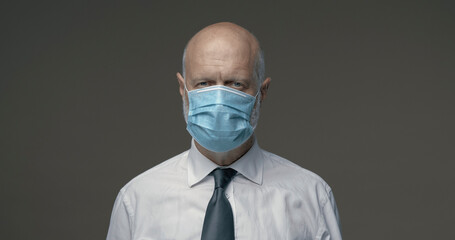 Middle-aged businessman posing with a surgical mask